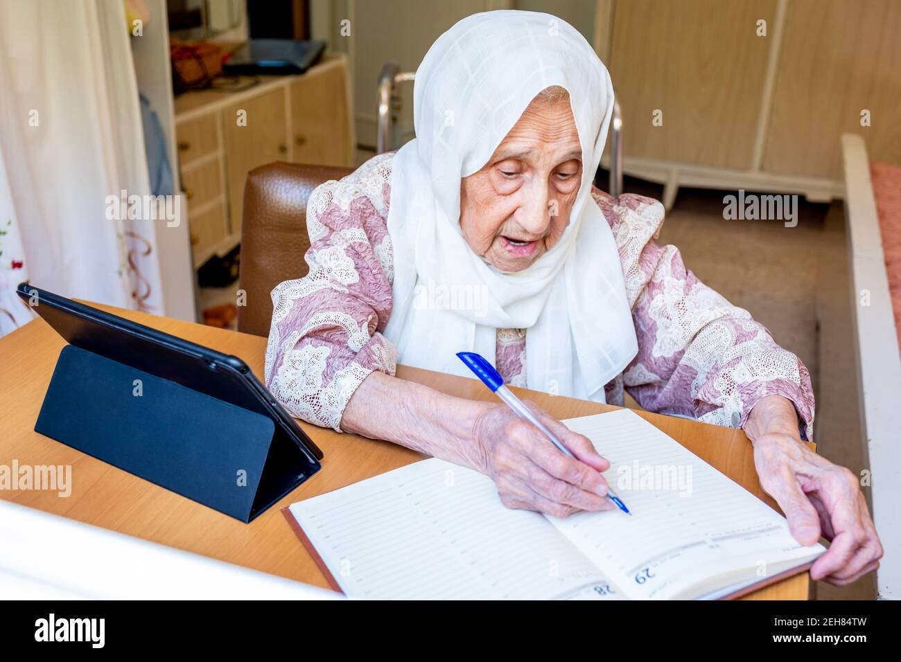 Old woman portrait studying ,writing and learning using tablet and notebook Stock Photo