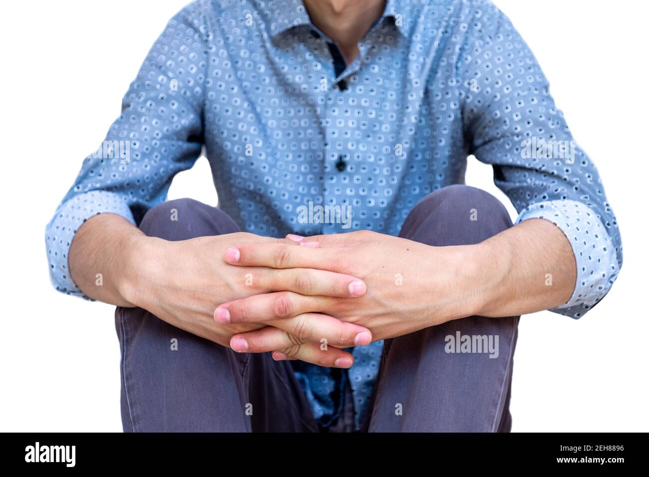Guy sitting on the ground holding his legs with his hands Stock Photo