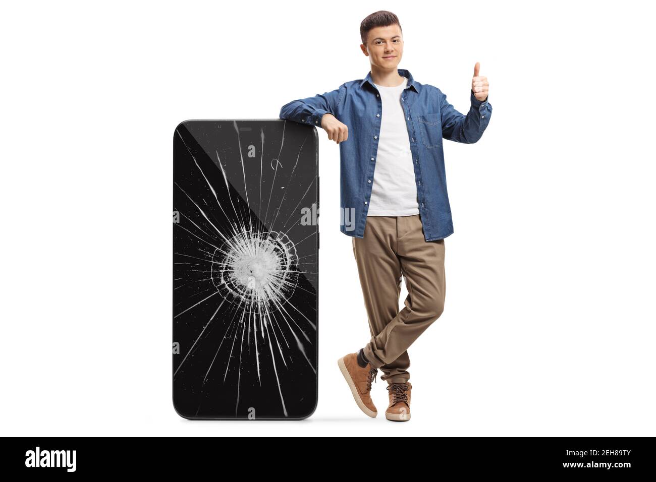 Young man leaning on a mobile phone with a broken screen and showing thumbs up isolated on white background Stock Photo