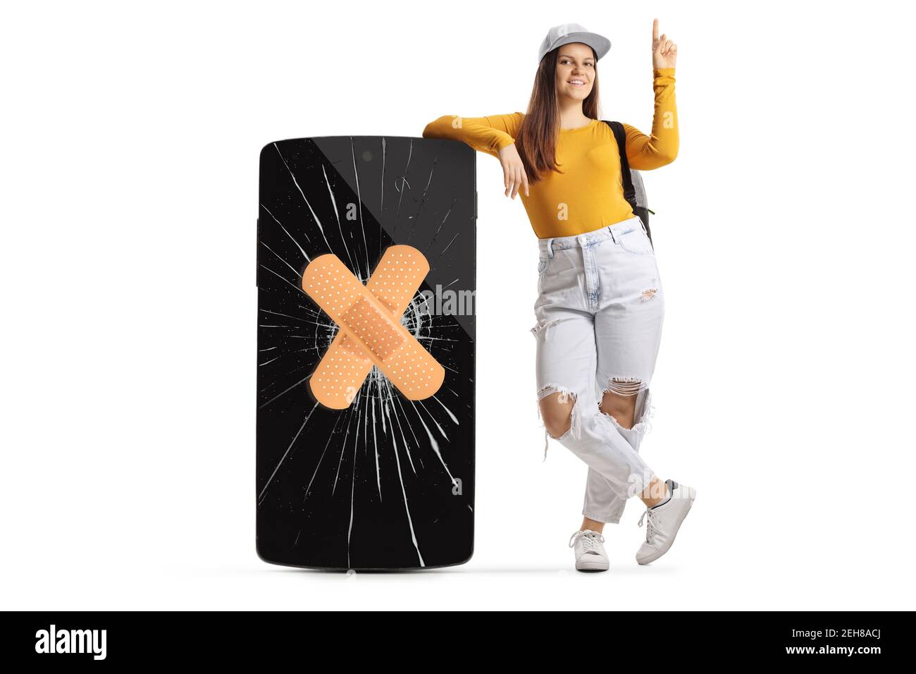 Full length portrait of a female student leaning on a big phone with a broken screen and band aid and pointing up isolated on white background Stock Photo