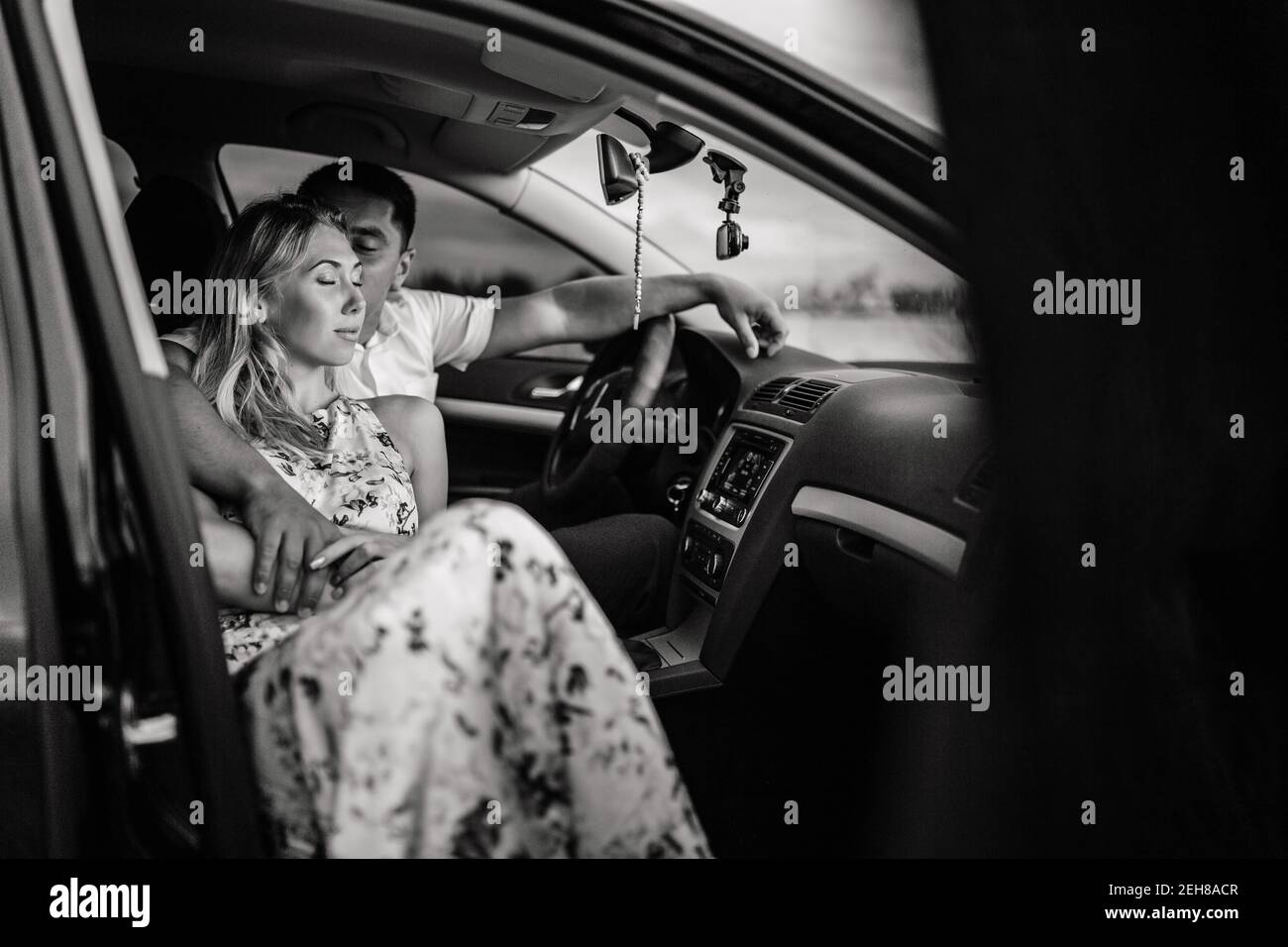 Happy couple sitting in a car and kissing. Man kissing woman Stock Photo