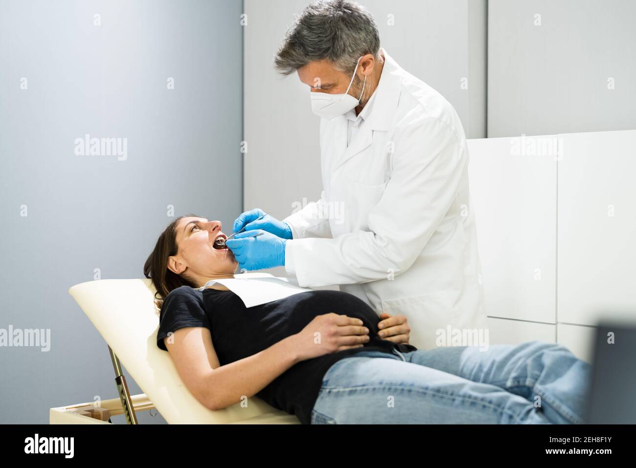 Pregnant Woman Tooth Decay. Dentistry Check By Dentist In Face Mask Stock Photo