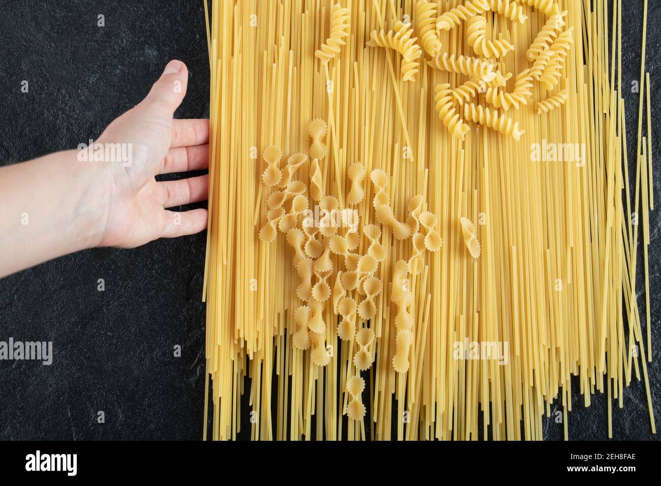Woman hands touching various pasta on dark surface Stock Photo