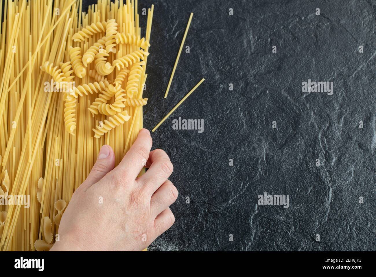 Female hands touching various pasta on dark surface Stock Photo