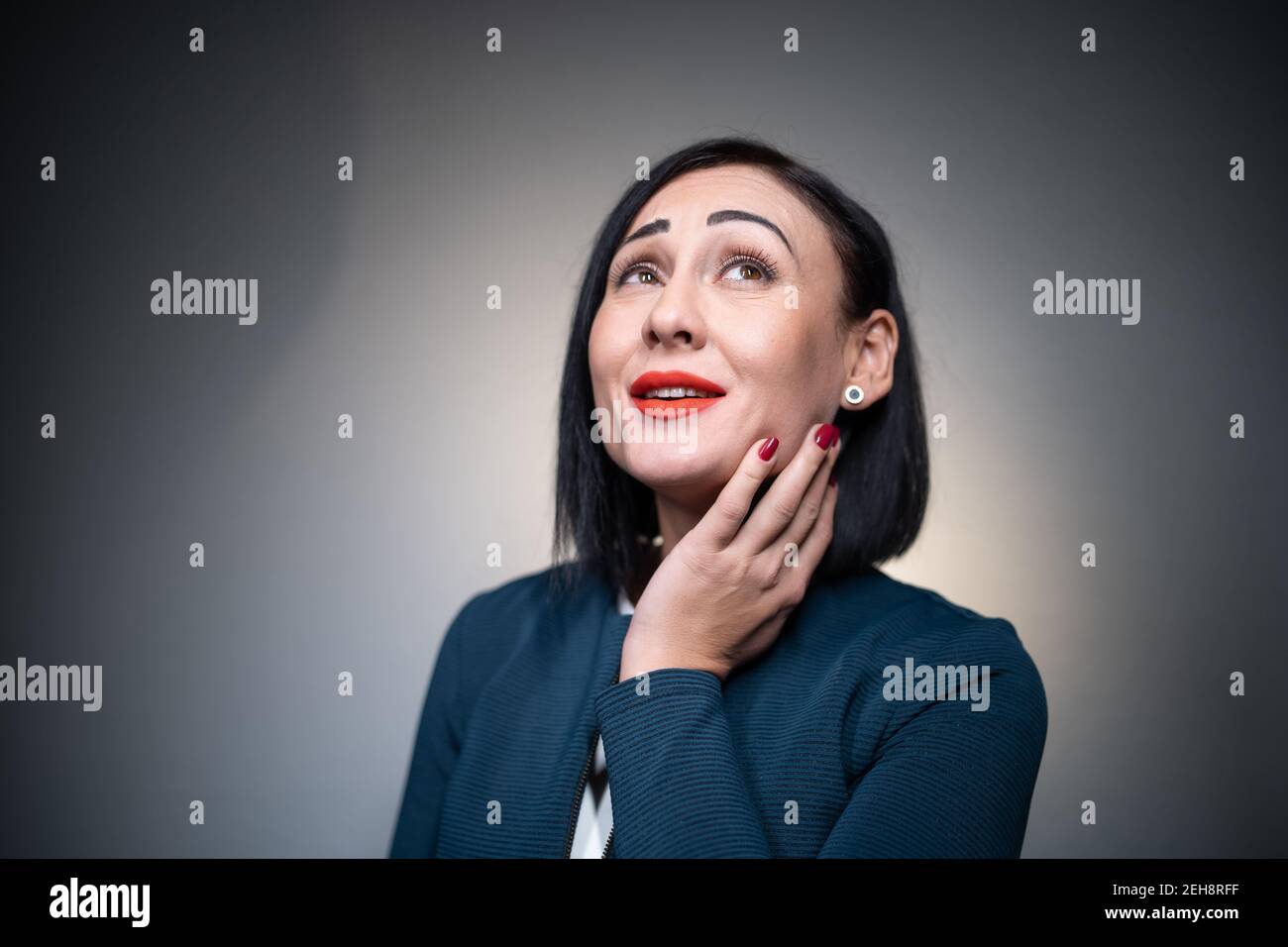 closeup of pretty happy female with dreamy emotion on grey background Stock Photo