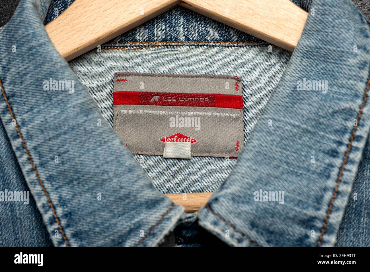 Lee Cooper label with slogan or motto on woman's denim jacket hanging on wooden hanger Stock Photo