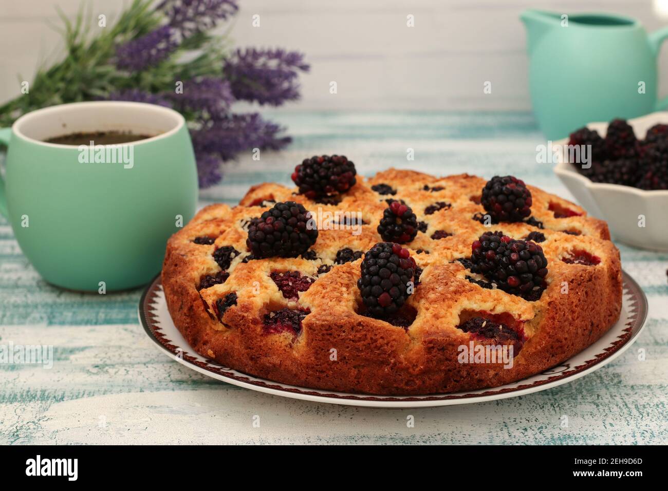 Homemade pie with blackberries and coconut chips on a light blue background. Closeup Stock Photo
