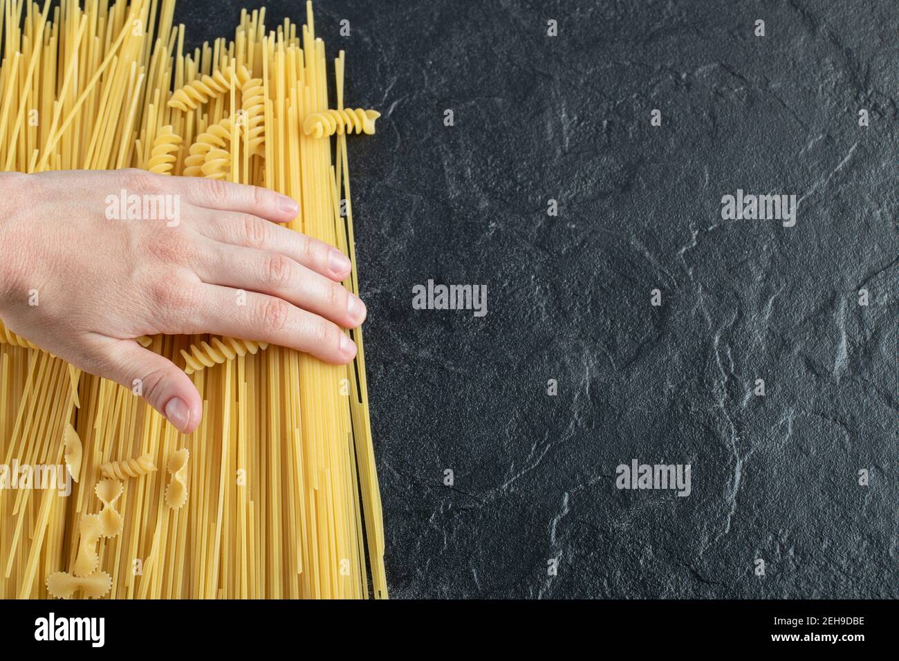 Female hands touching various pasta on dark surface Stock Photo
