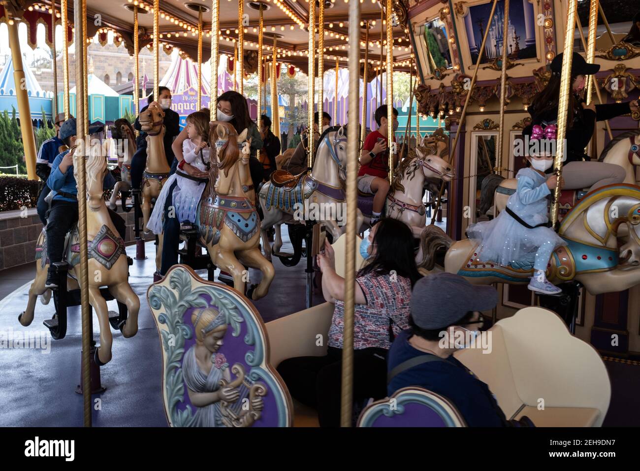Visitors wearing face masks as a precaution against the spread of coronavirus, ride the Cinderella Carousel during the reopening of Hong Kong Disneyland Park as government loosens coronavirus (Covid-19) social-distancing measures. Stock Photo