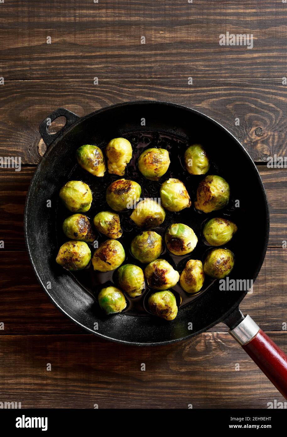 Roasted brussles sprouts in frying pan on wooden background. Top view, flat lay Stock Photo