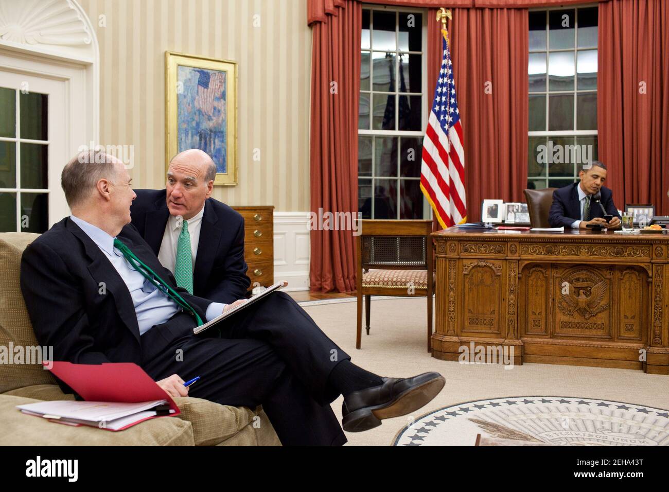 Chief of Staff Bill Daley confers with National Security Advisor Tom Donilon, left, as President Barack Obama talks on the phone in the Oval Office, March 17, 2011. Stock Photo