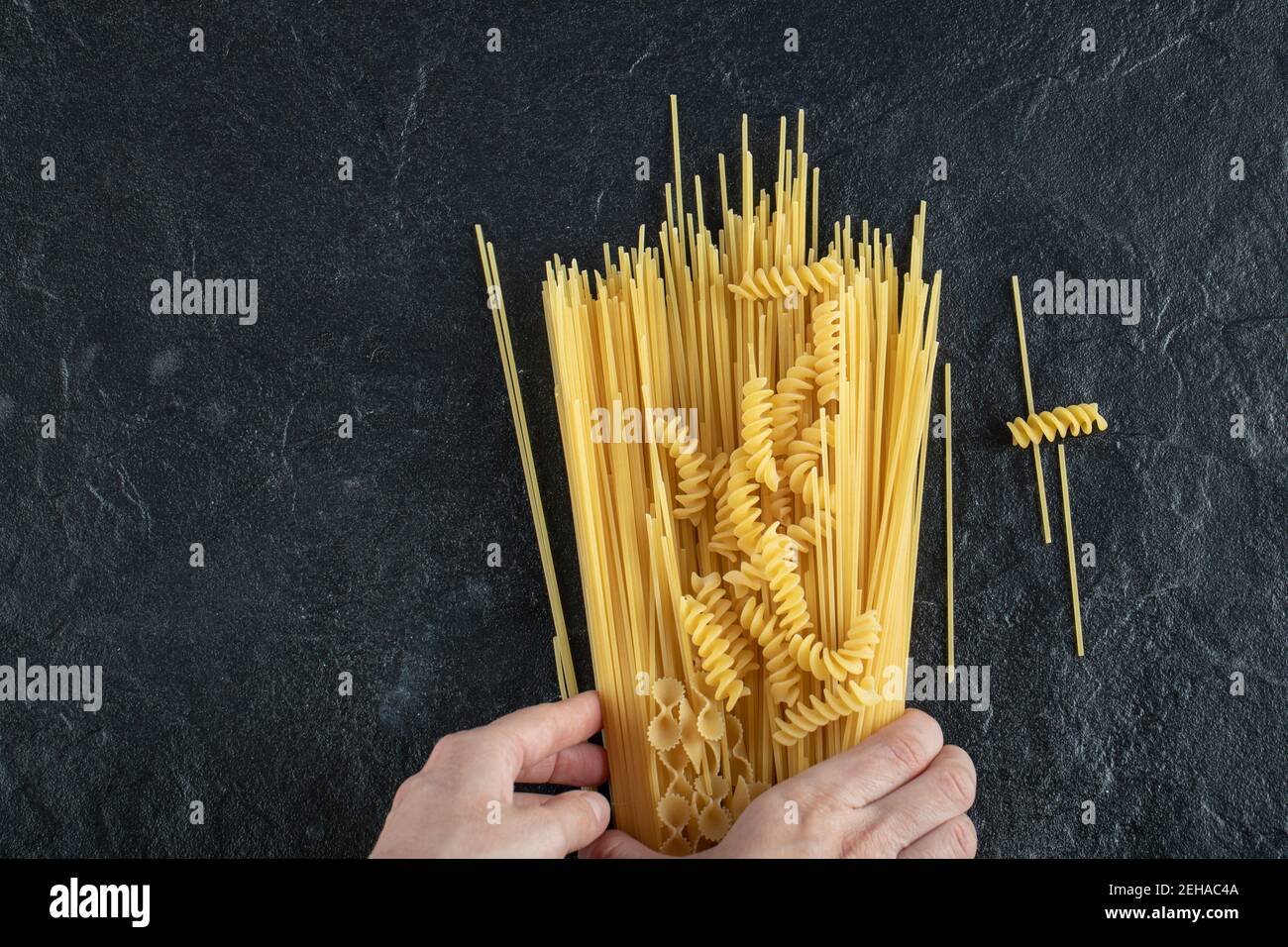 Woman hands touching various pasta on dark surface Stock Photo