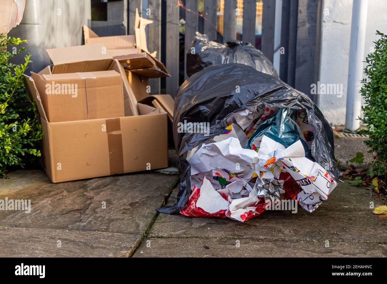 https://c8.alamy.com/comp/2EHAHNC/christmas-household-waste-consisting-of-boxes-and-wrapping-paper-beside-a-bin-or-trash-can-in-a-garden-2EHAHNC.jpg