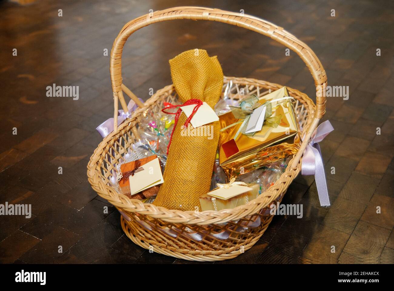 Gifts inside a wicker basket. Boxes and bottle wrapped with labels with