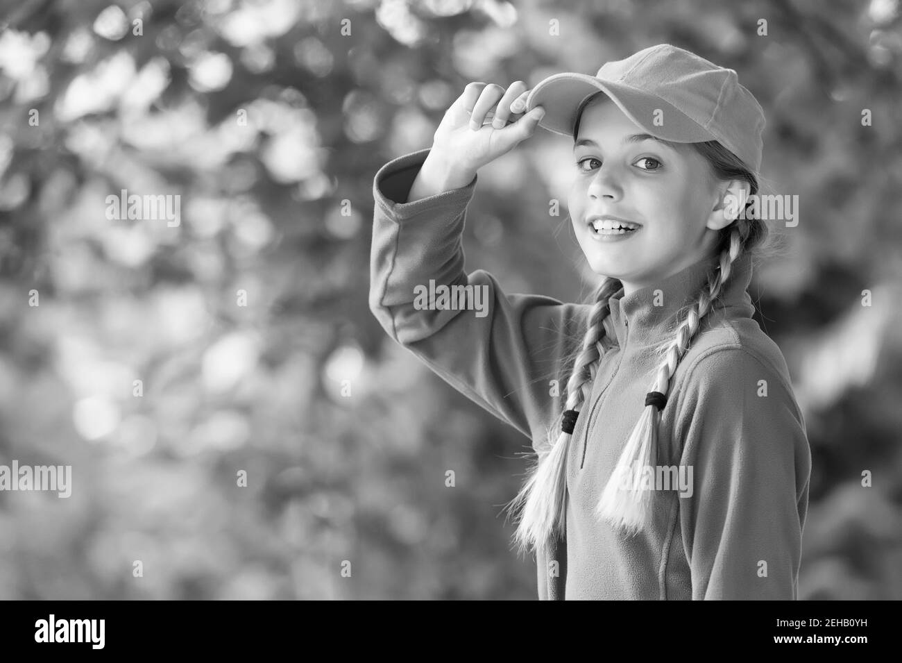 Her style is a lot more casual. Happy child in casual style natural  outdoors. Little girl wear baseball cap. Casual wardrobe. Childrens clothing.  Summer fashion. Trendy everyday clothes, copy space Stock Photo 