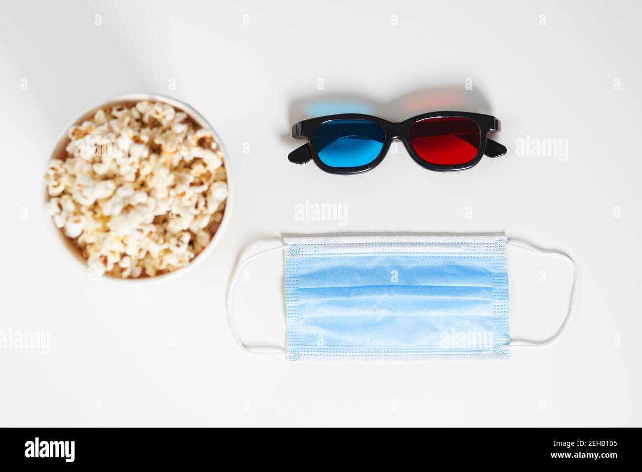 Above view of popcorn, mask and 3D glasses on white background. Concept ...