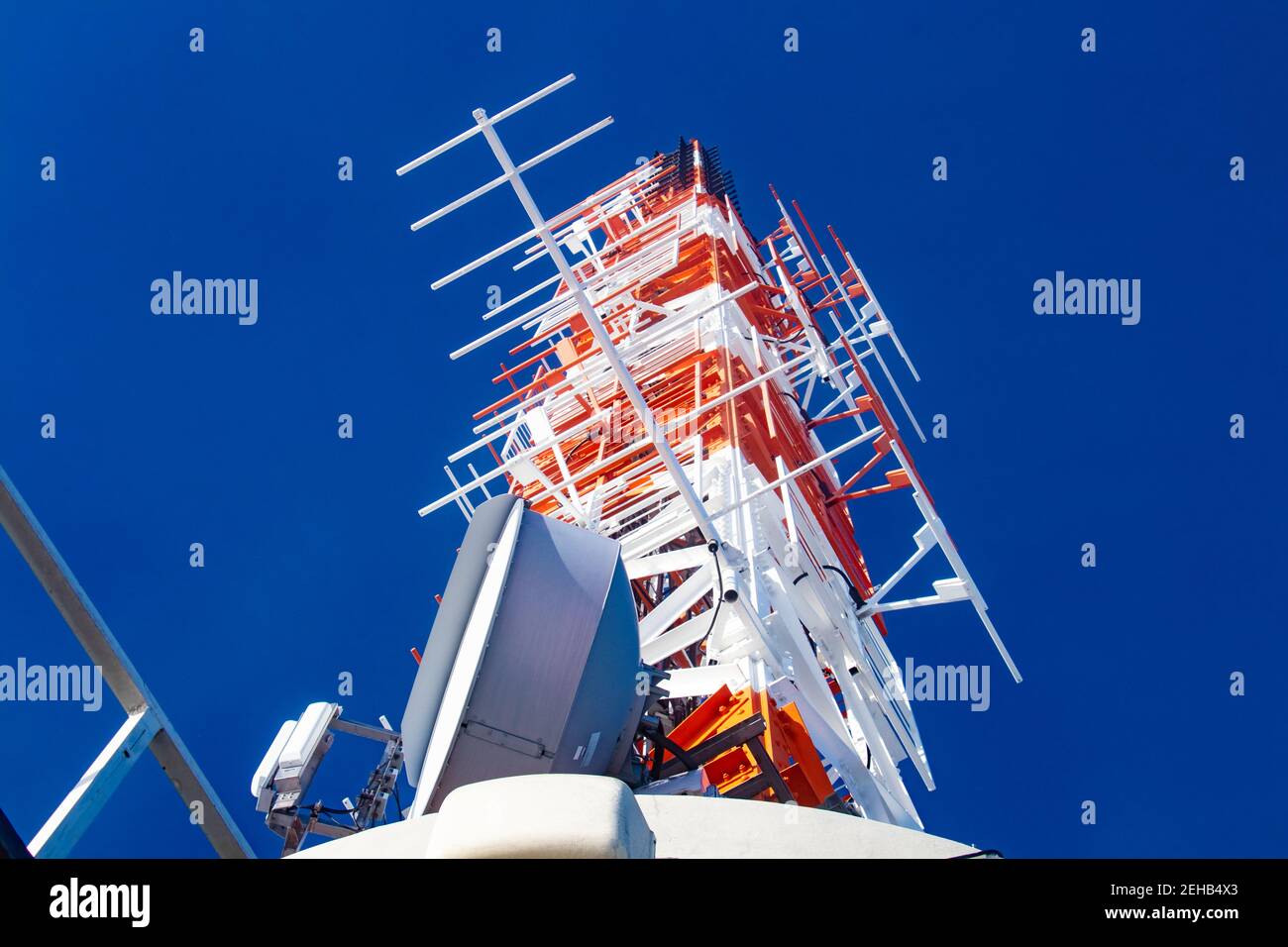 Antenna mast on top of Stuttgart TV Tower  red and white technical structure against blue sky Stock Photo