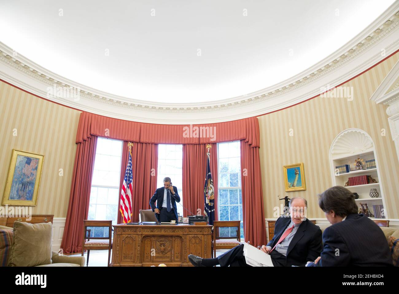 President Barack Obama talks on the phone with President Vladimir Putin of Russia in the Oval Office, March 1, 2013. National Security Advisor Tom Donilon speaks with Tony Blinken, Deputy National Security Advisor, right. Stock Photo