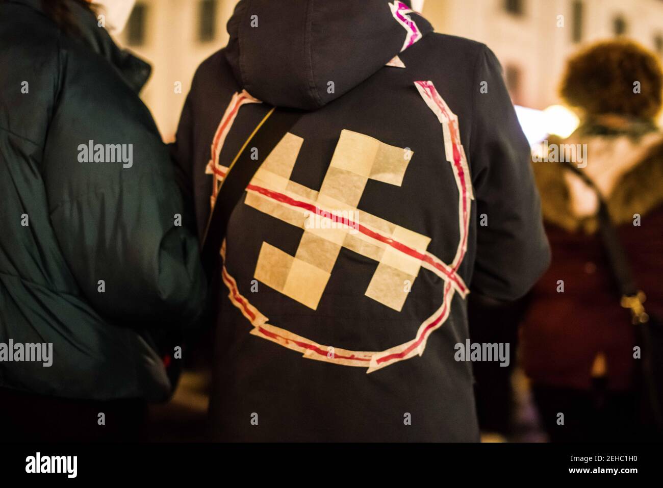 Munich, Bavaria, Germany. 19th Feb, 2021. A demonstrator against Nazis has a Swastika (Hakenkreuz) crossed out on her back. Scenes from the Munich one-year memorials for the victims of the Hanau terror attack in Germany committed by Tobias R. Some 400 memorial participants were later joined by over 750 antifascists and civic groups at Munich's Stachus. Credit: ZUMA Press, Inc./Alamy Live News Stock Photo