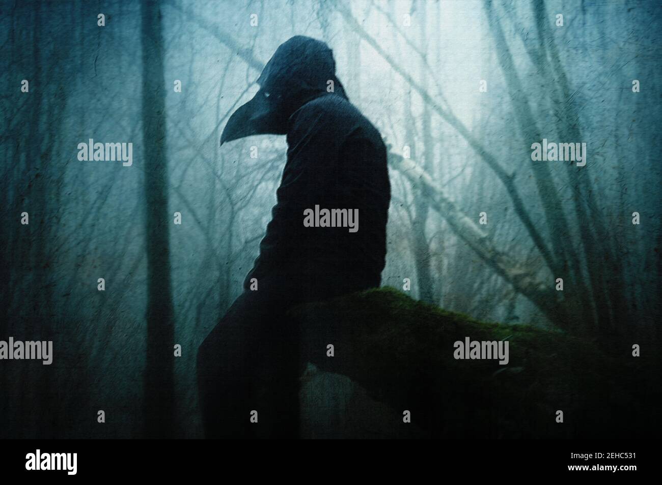 A horror concept of a spooky hooded figure in a plague doctor mask. Sitting in a forest on a winters day. With a grunge, artistic, edit Stock Photo