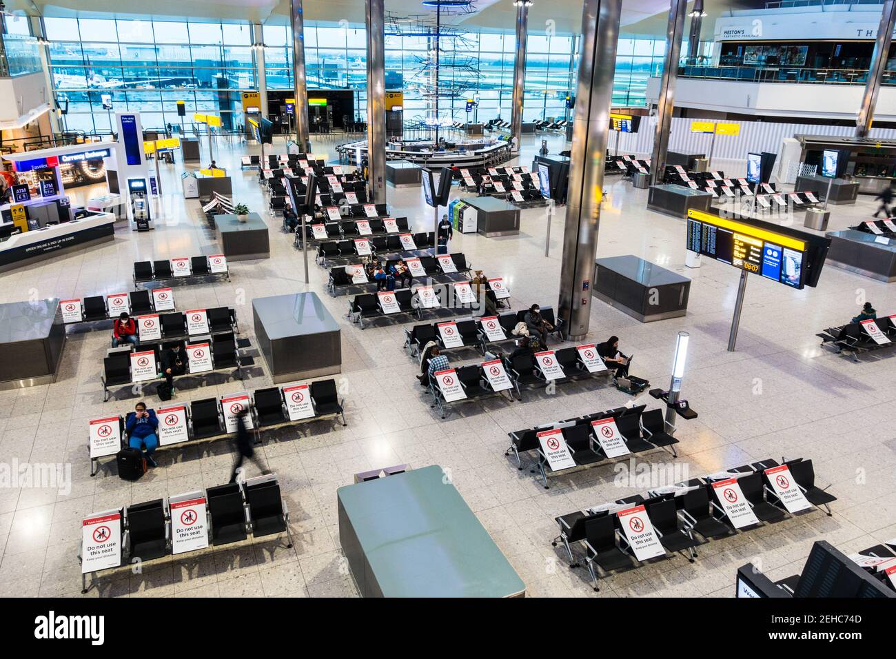 Pandemic air travel social distancing at London Heathrow airport terminal building seating area with placards placed on alternate seats Stock Photo