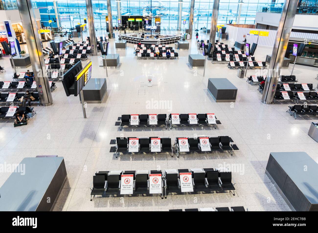 Pandemic air travel social distancing at London Heathrow airport terminal building seating area with placards placed on alternate seats Stock Photo