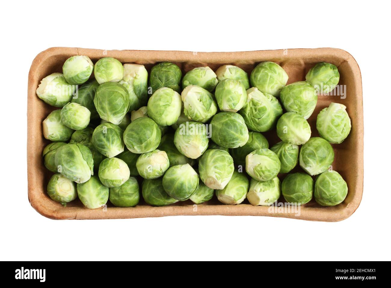 The heads of Brussels sprouts are randomly placed in a cardboard box. Box isolated on a white background.. Closeup. View from above Stock Photo