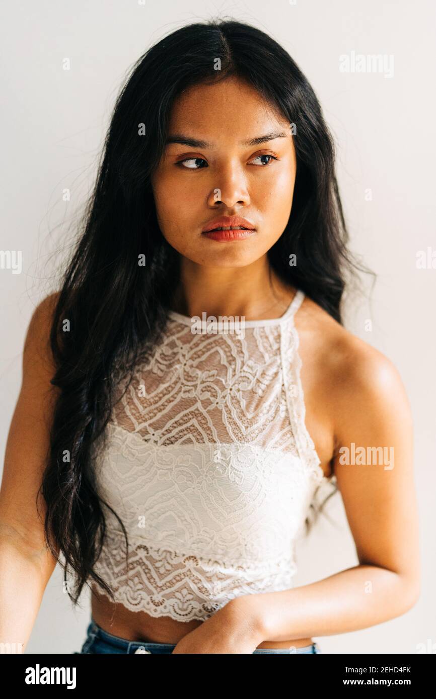Long hair brunette Asian Woman wearing a white top and looking away ...