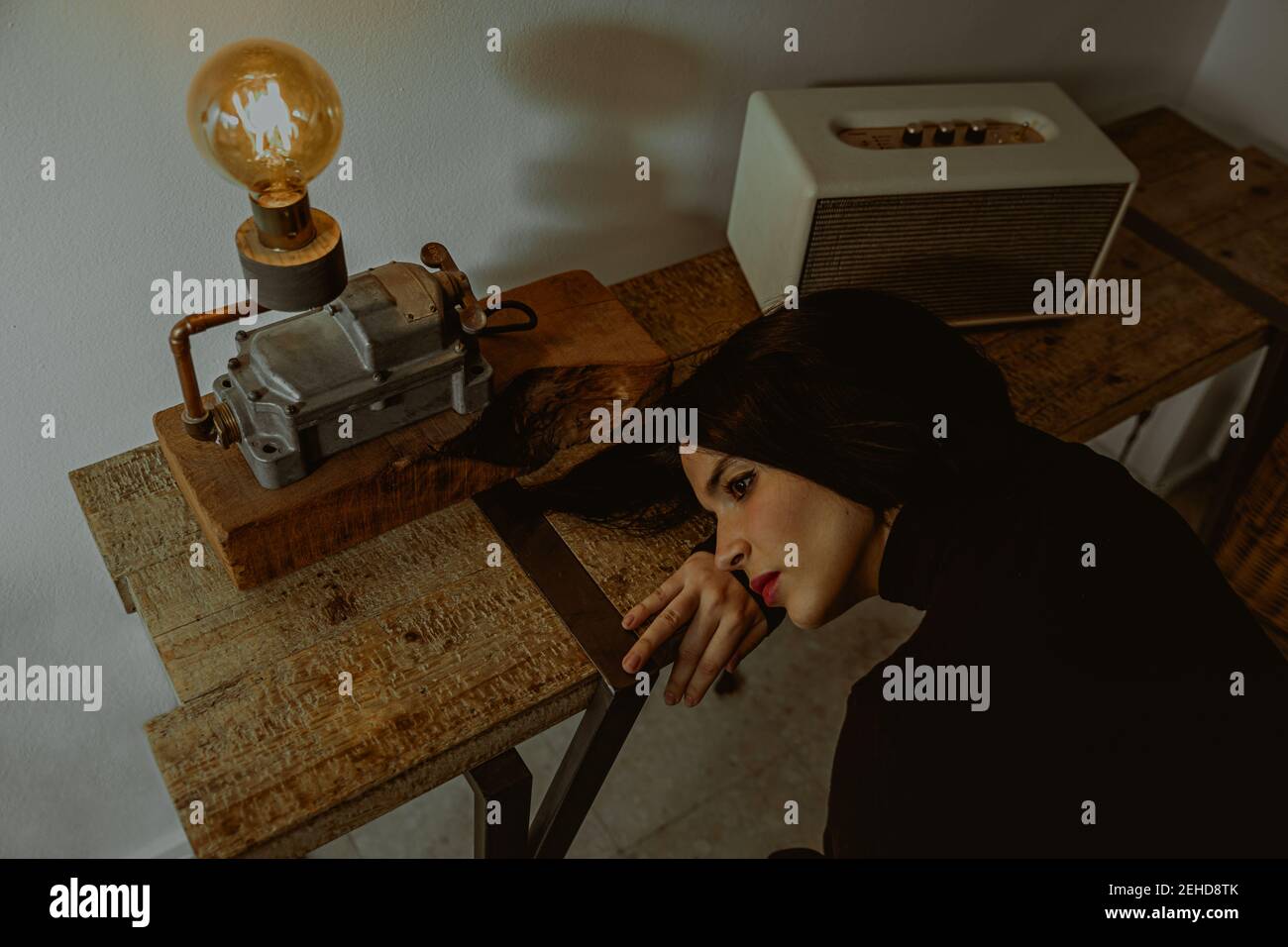High angle of dreamy female leaning on table in retro room and looking away Stock Photo