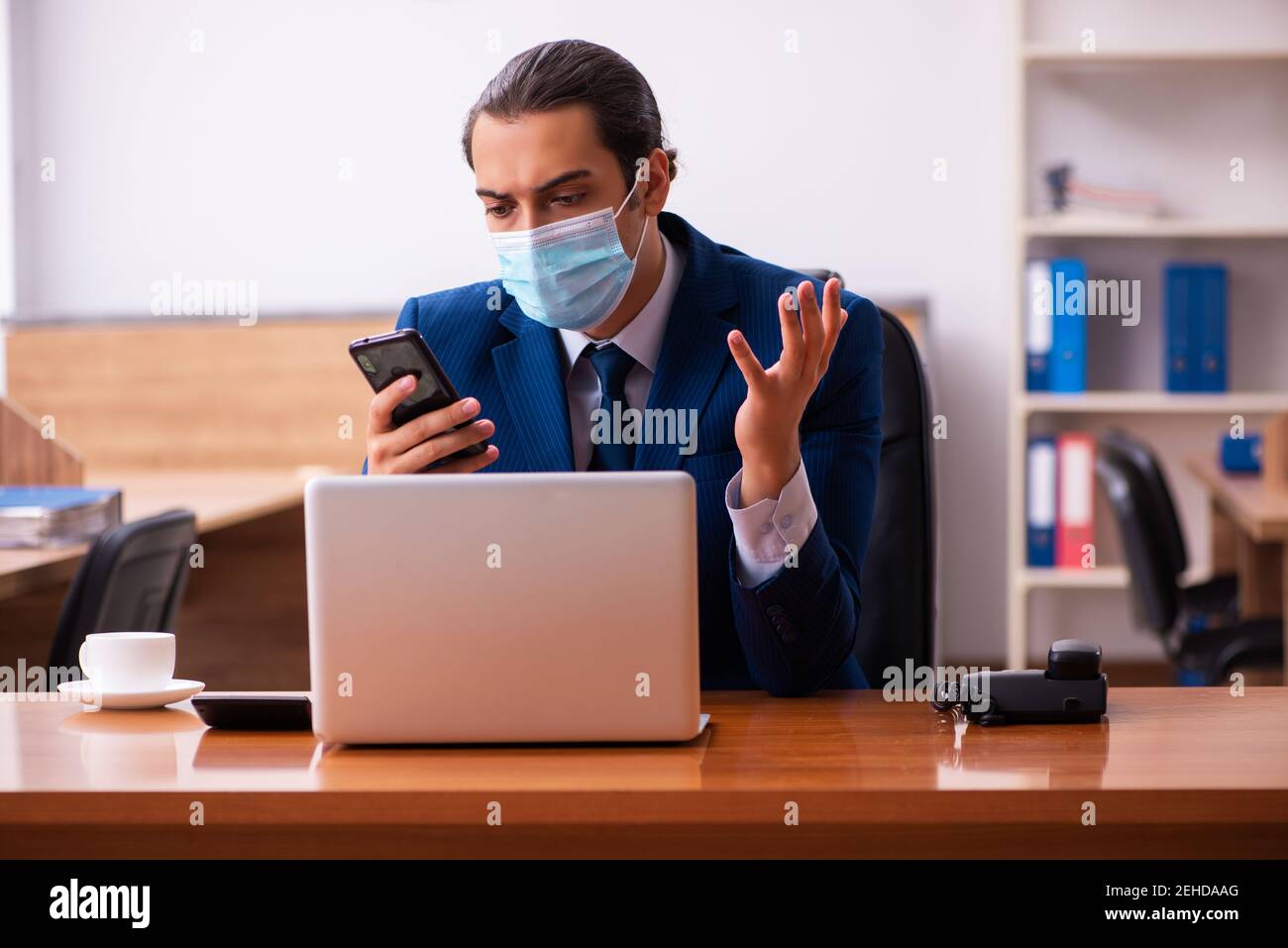 Young employee working in the office wearing mask Stock Photo - Alamy