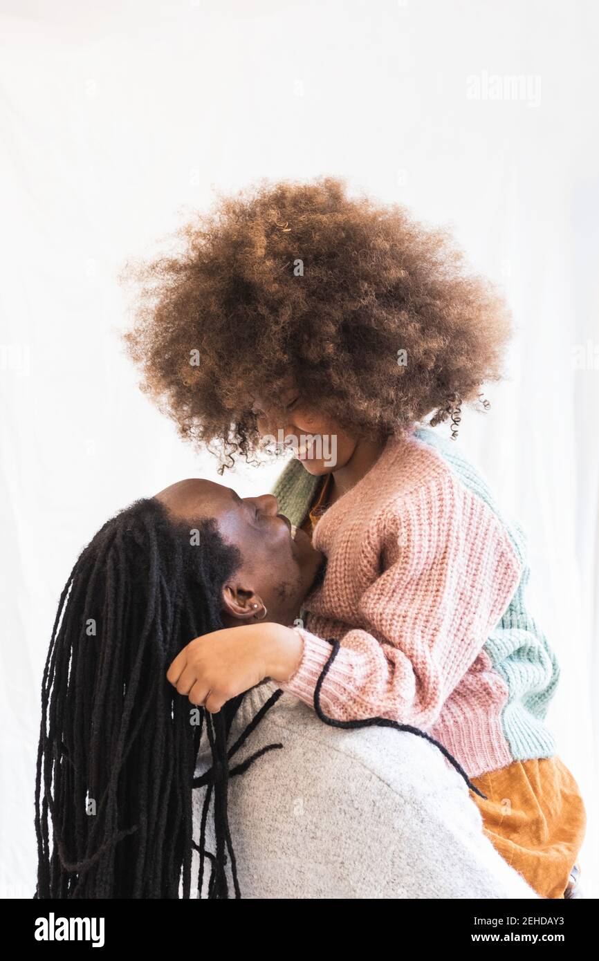 Side view of happy African American father embracing daughter while ...