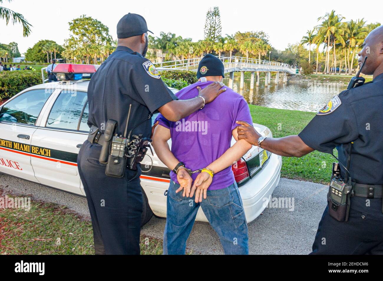 North Miami Beach Florida,Police Department,Black policeman policemen arresting man wearing handcuffs, Stock Photo