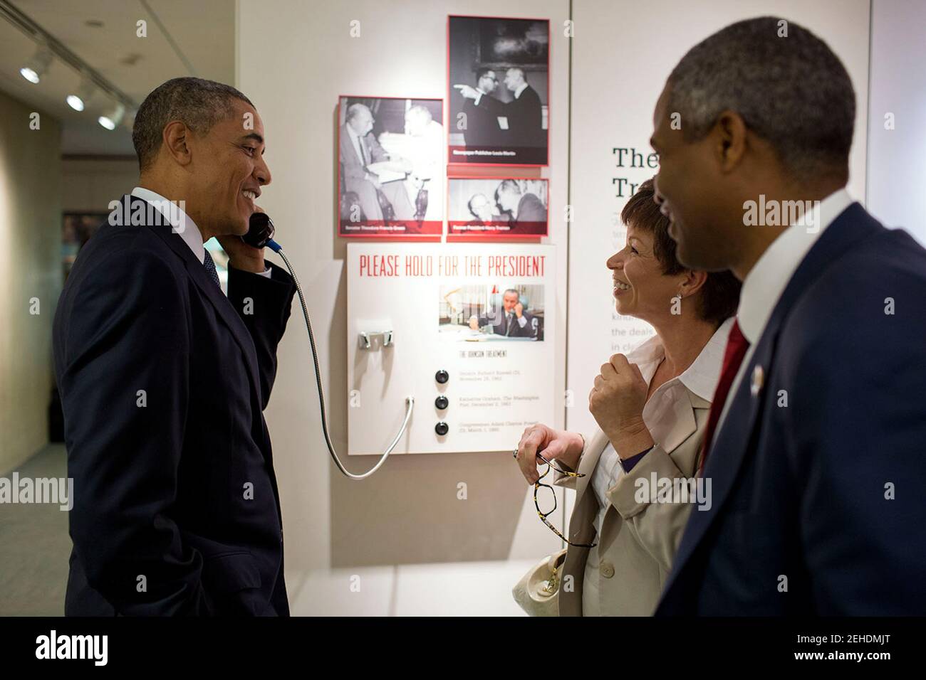 President Barack Obama, with Senior Advisor Valerie Jarrett and Marty Nesbitt, founding board member of The Barack Obama Foundation, listens to a recording of a President Johnson phone call during a tour of the Lyndon Baines Johnson Presidential Library in Austin, Texas, April 10, 2014. Stock Photo