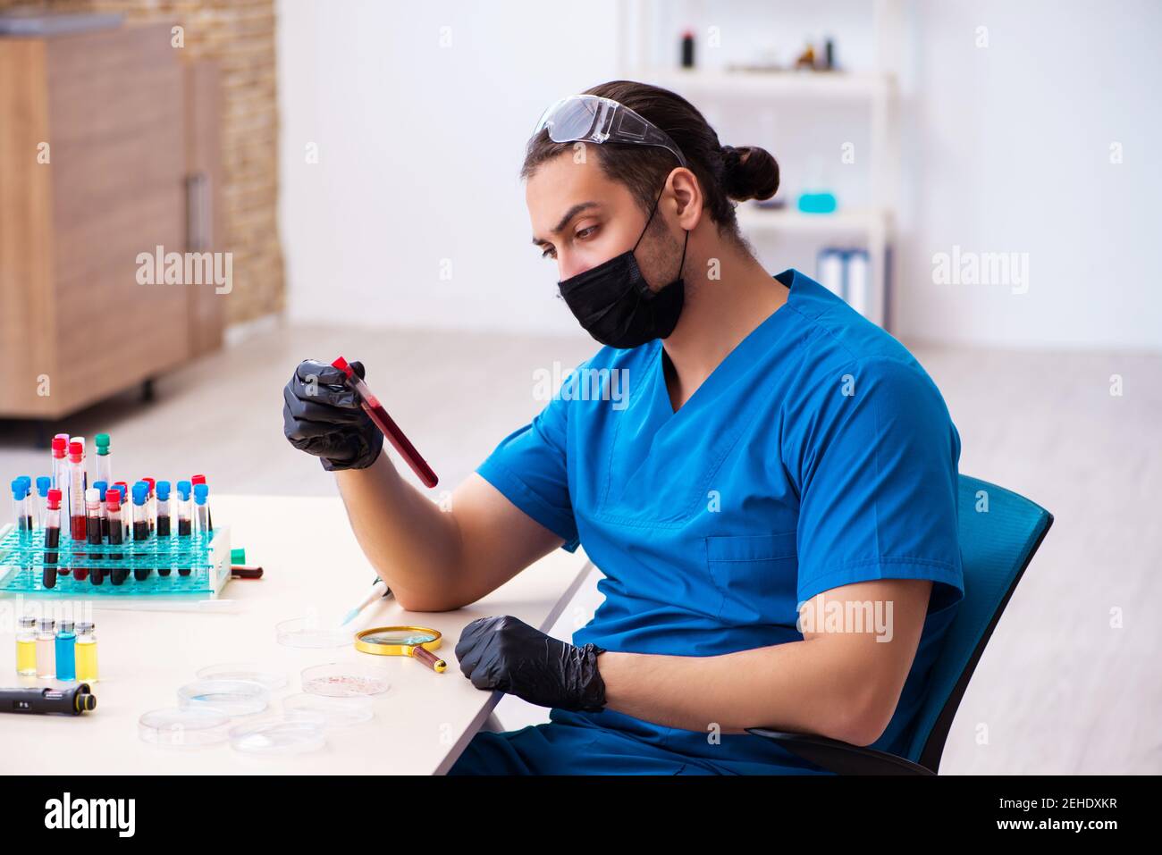 Male biochemist testing blood samples in pandemic concept Stock Photo ...