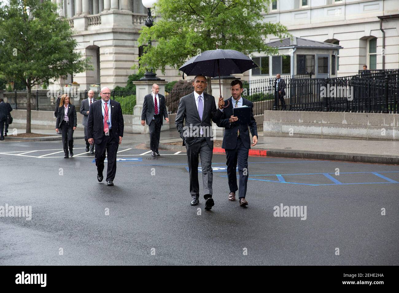 President Barack Obama holds an umbrella as he walks in the rain with Brian Mosteller, Director of Oval Office Operations, across West Executive Avenue to the West Wing of the White House, June 12, 2014. Stock Photo