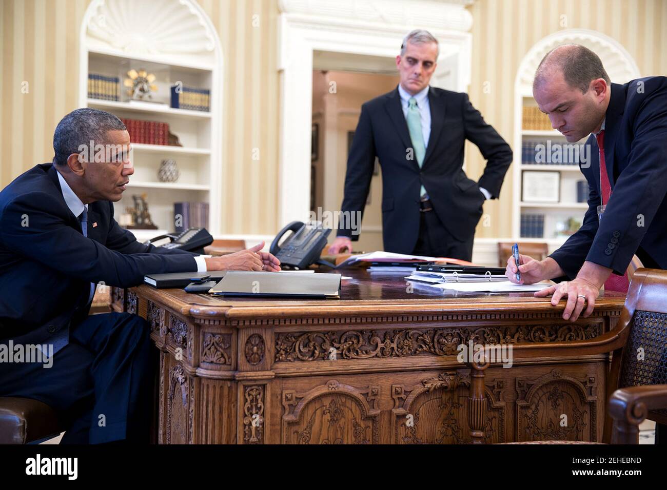 President Barack Obama meets with Chief of Staff Denis McDonough and Ben Rhodes, Deputy National Security Advisor for Strategic Communications, right, in the Oval Office, Aug. 7, 2014. Stock Photo