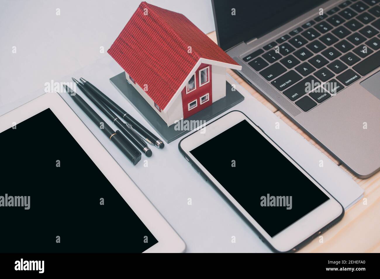 Phone laptop computer tablet house model equipment pen on desk
