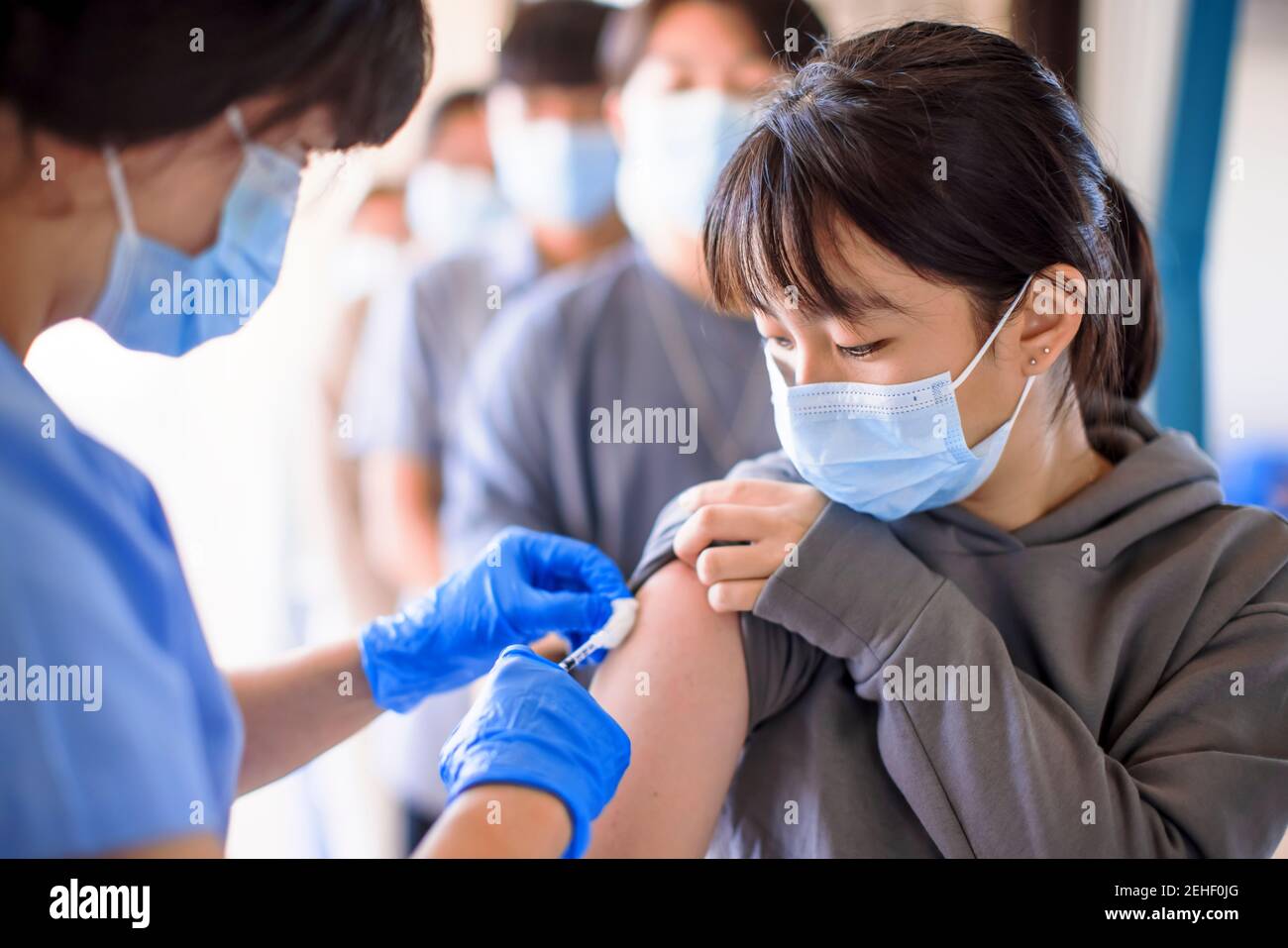 Doctor injecting vaccine for young people Stock Photo