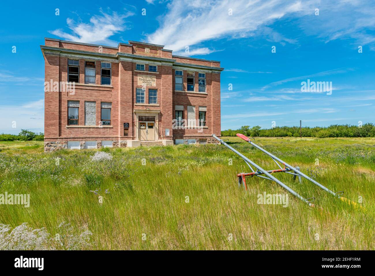 The old, abandoned Aneroid Consolidated School in Aneroid, Saskatchewan, Canada with teeter totters in the foreground Stock Photo