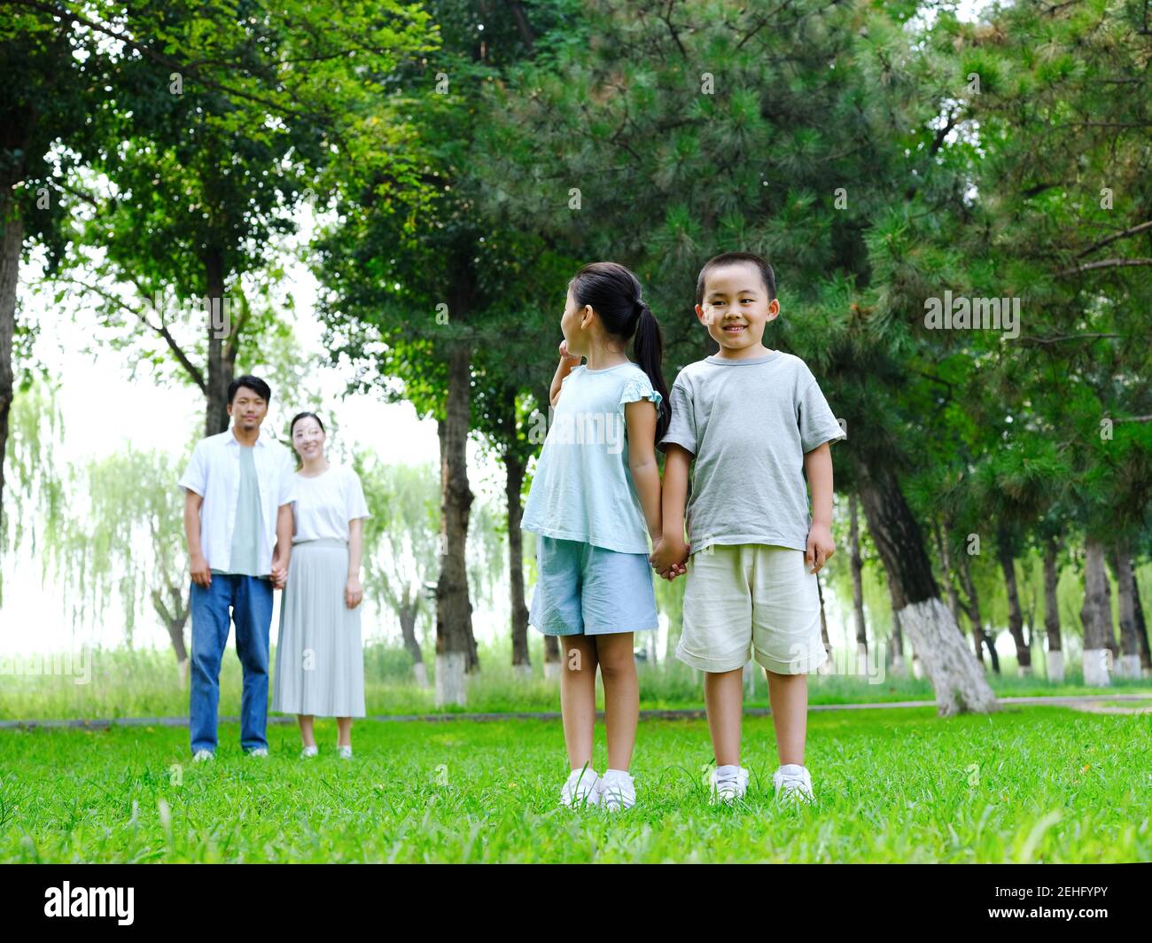 Happy family of four playing in the park standing Stock Photo - Alamy