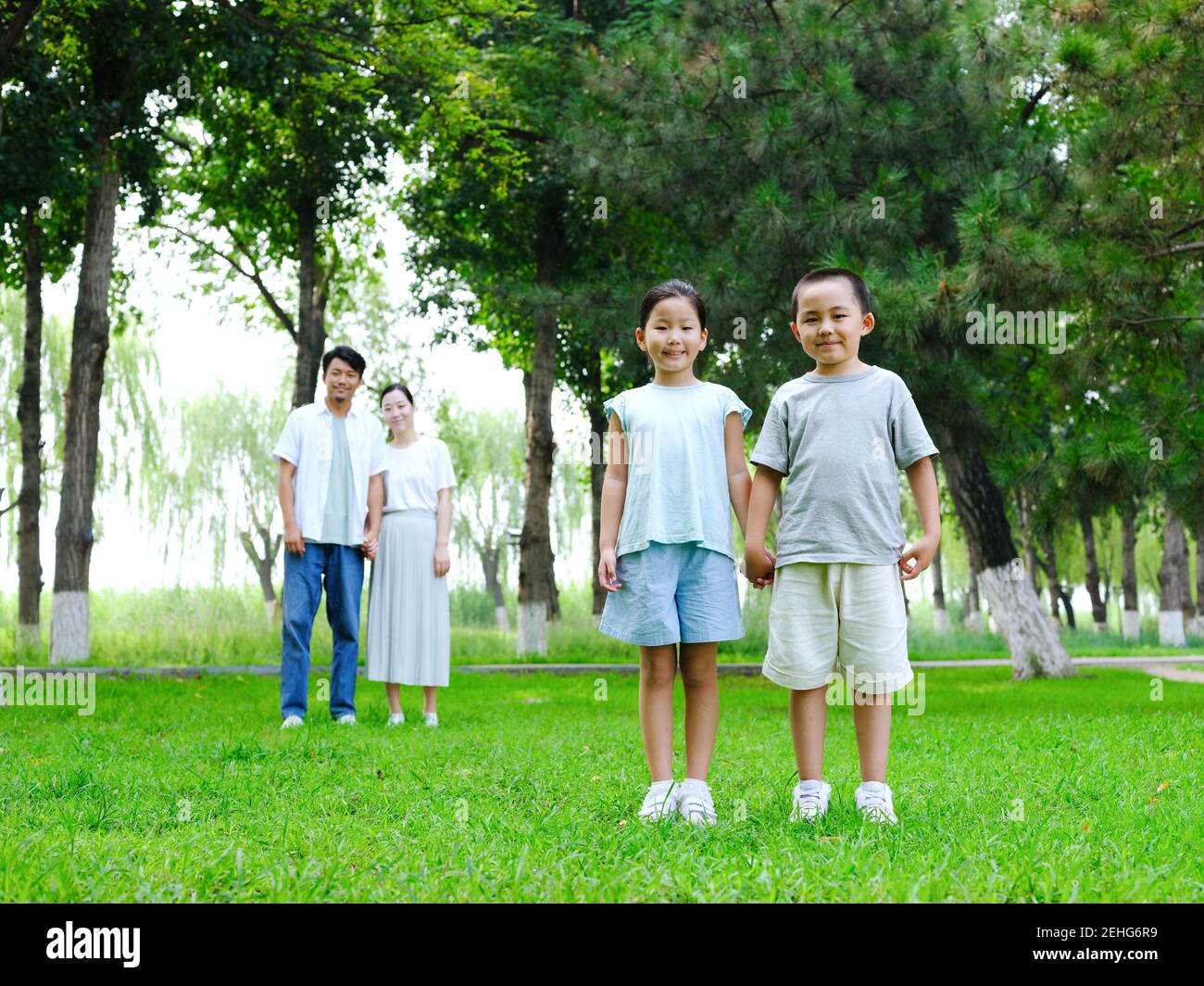 Happy family of four playing in the park standing Stock Photo - Alamy