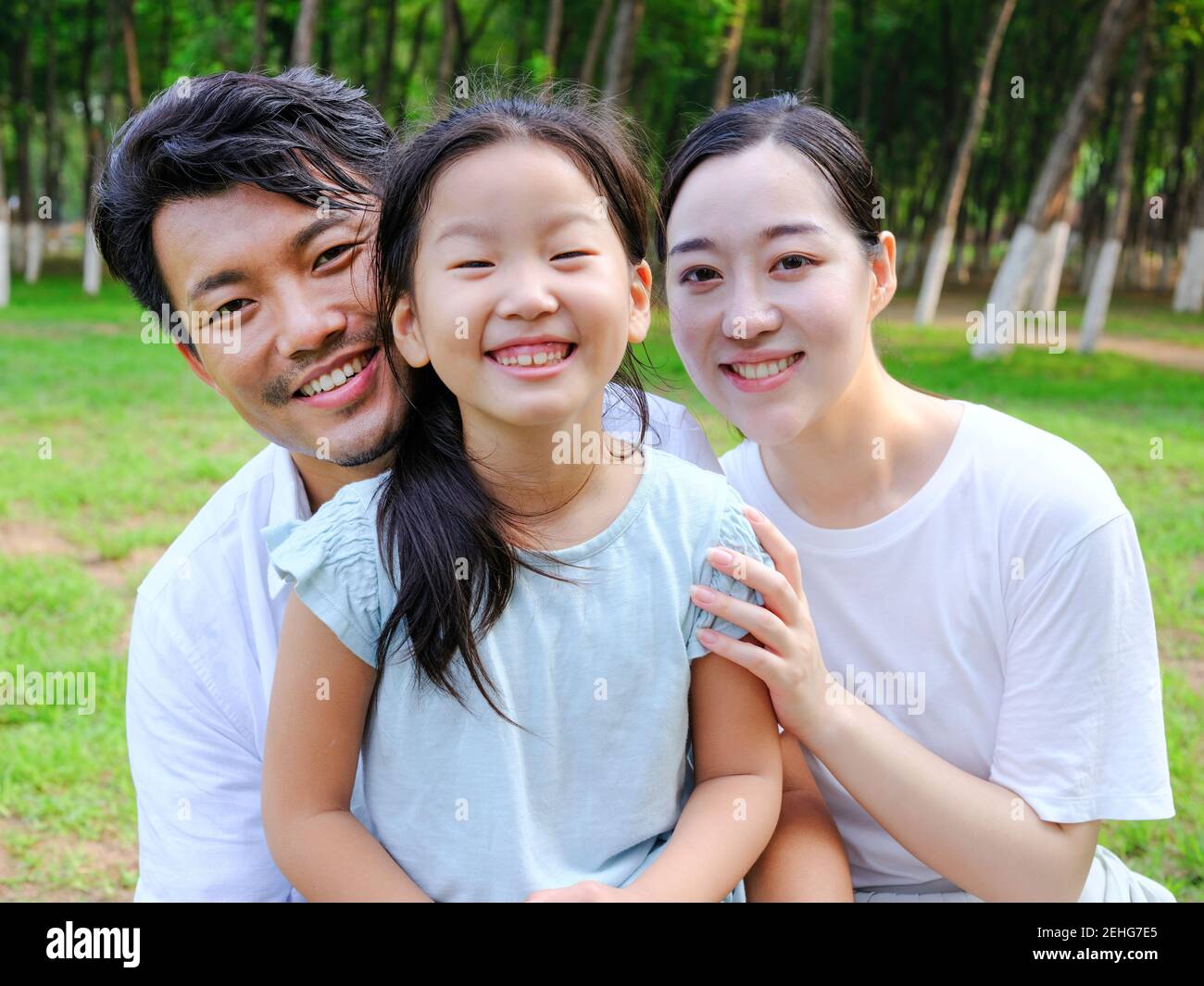 Happy family of three playing in the park smiling Stock Photo - Alamy