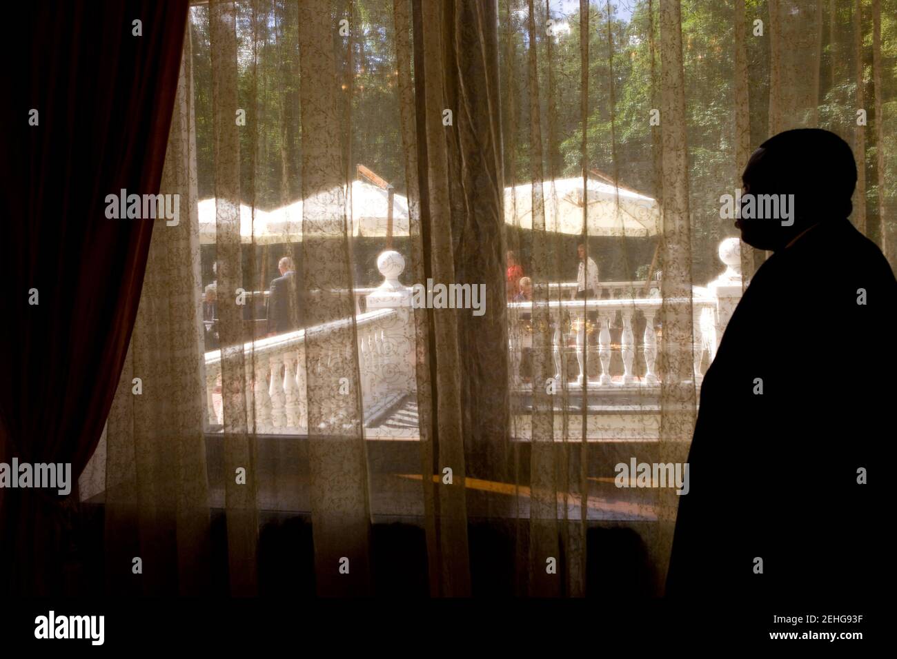 A member of the traveling White House support staff looks through a drape where President Barack Obama was having a breakfast meeting with Prime Minister Vladimir Putin at Putin's dacha, located outside of Moscow, Russia, July 7, 2009. Stock Photo