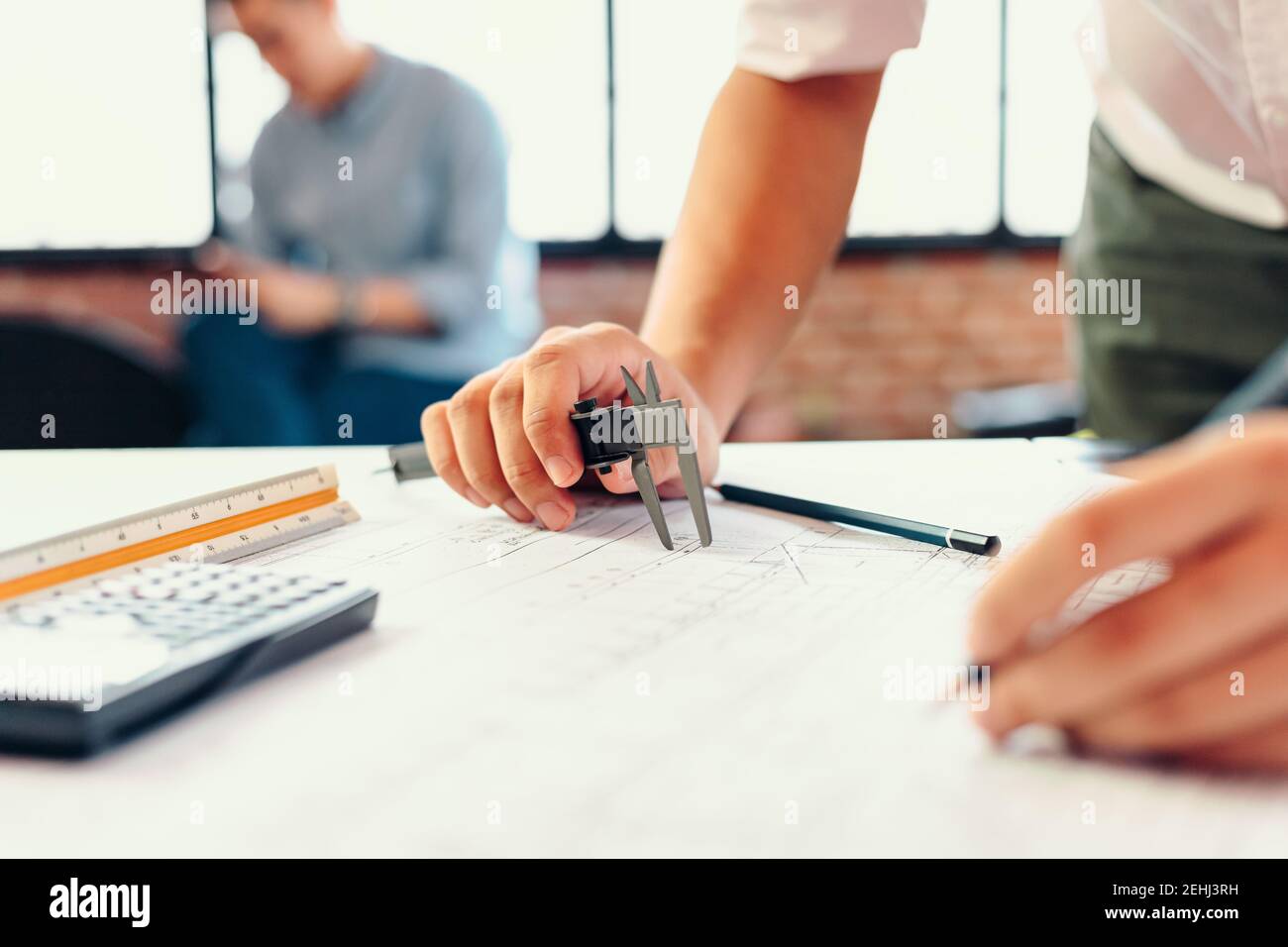 Engineering hands hold vernier caliper working and checking drawing blue print scale on workplace. Stock Photo