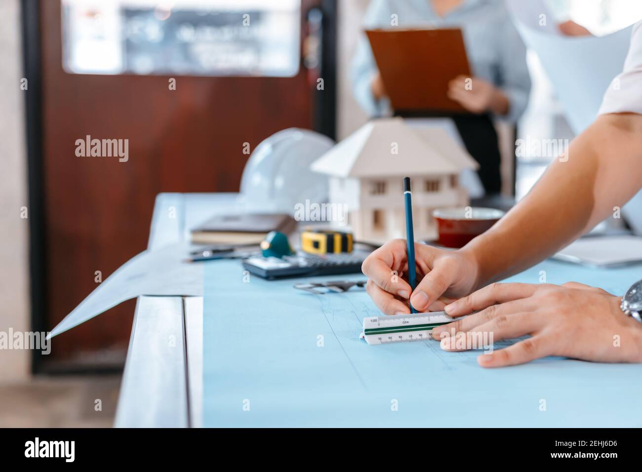 engineers holding a pen pointing to a building and drawing outlay ...