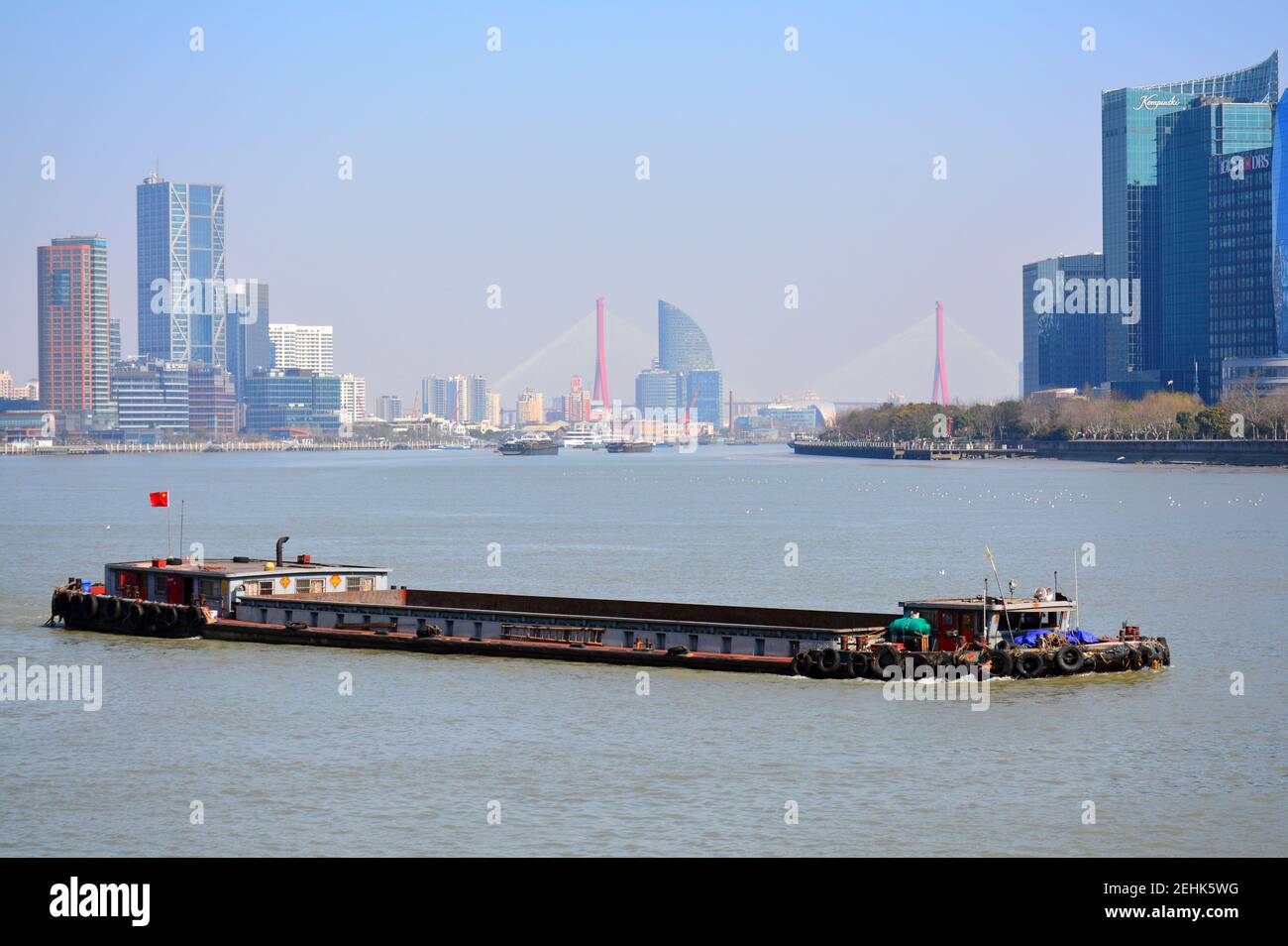 Barge transports goods along the Huangpu river, part of the Beijing to Hangzhou grand canal. Pudong district in the background. Feb 2021 Stock Photo