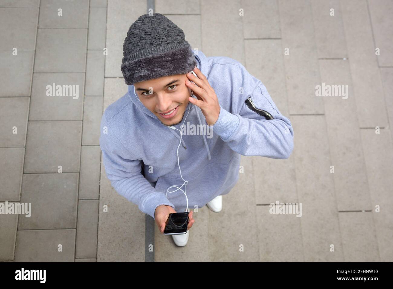 Listening to music smiling young latin man runner sports training from above outdoor Stock Photo