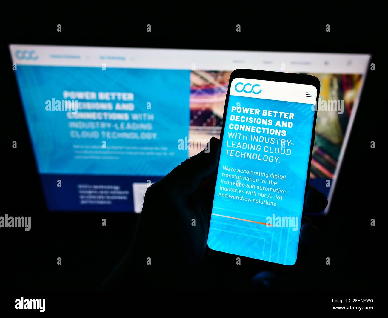 Person holding smartphone with website and logo of American software company CCC Information Services Inc. on screen. Focus on phone display. Stock Photo