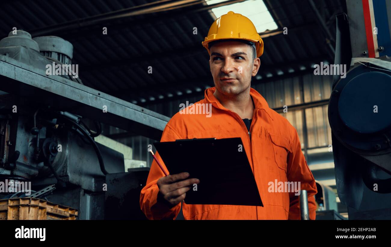 Skillful factory worker working with clipboard to do job procedure