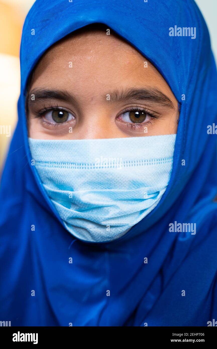 Head shot o Muslim Girl with hijab and medical face mask looking at